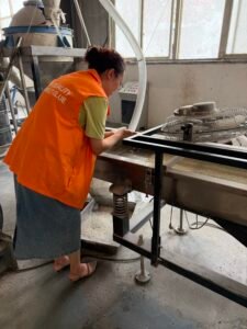 Factory worker performing inspection on hot melt adhesive production equipment