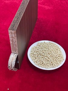 Edge‑banded wood board sample next to hot‑melt glue granules for quality test